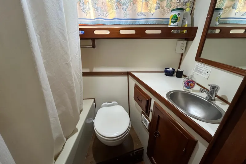 Slide: The Image of 1987 Marine Trader Sundeck bathroom with sink, toilet, and shower curtain. - 37