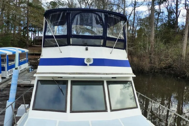 Slide: The Image of 1987 Marine Trader Sundeck boat docked in a wooded area. - 7