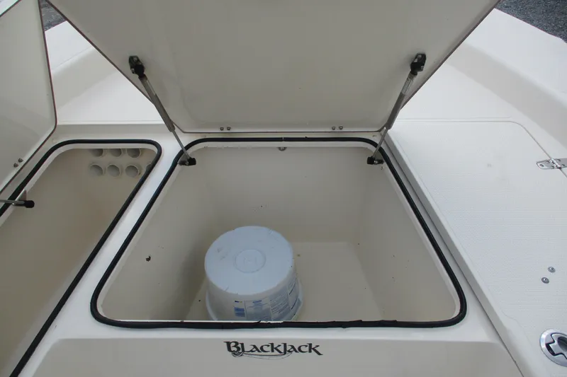 Slide: The Image of Open storage compartment on 2016 BlackJack 256 Bay boat with a bucket inside. - 16