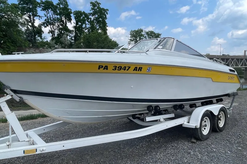 Slide: The Image of 1988 Donzi Open Bow boat on trailer, white with yellow stripe, parked outdoors. - 1