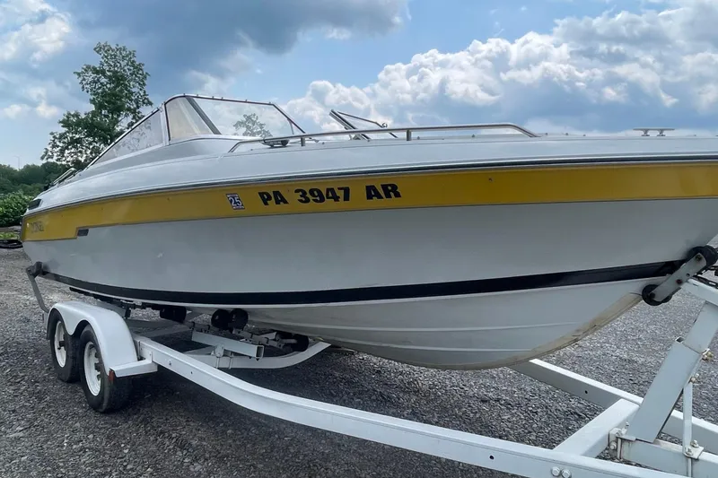 Slide: The Image of 1988 Donzi Open Bow boat on trailer, white with yellow stripe, under cloudy sky. - 5