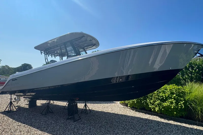 The Image of 2025 Edgewater 340CC boat displayed outdoors on stands, under clear blue sky. - 0
