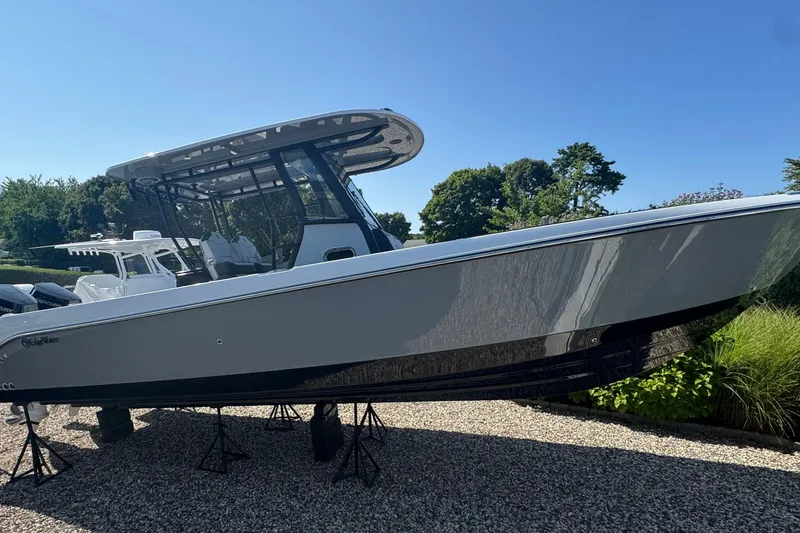Slide: The Image of 2025 Edgewater 340CC boat on display, elevated on stands, under clear blue sky. - 2