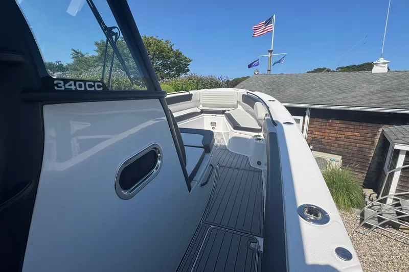 Slide: The Image of 2025 Edgewater 340CC boat interior with cushioned seating and speakers, under clear blue sky. - 33