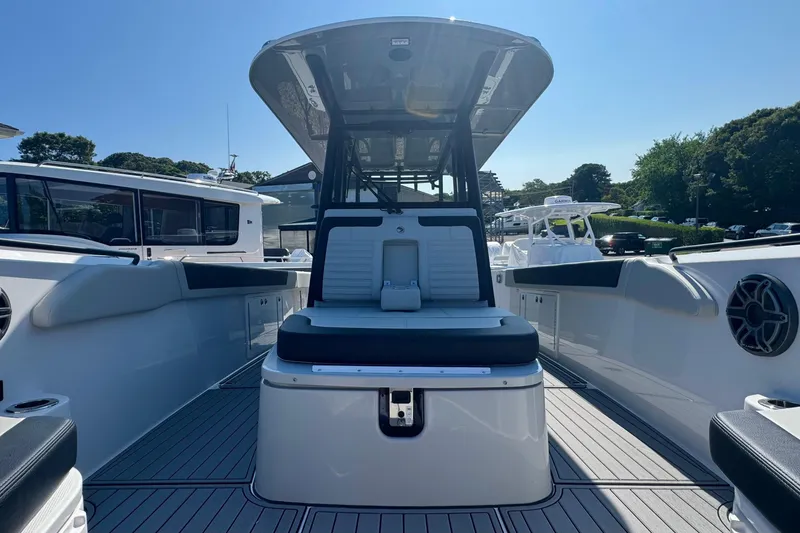 Slide: The Image of 2025 Edgewater 340CC boat deck with seating, docked near a building, flags waving. - 35