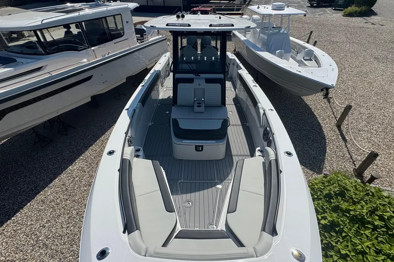 Slide: The Image of 2025 Edgewater 340CC boat interior with seating and canopy, docked under clear blue sky. - 37