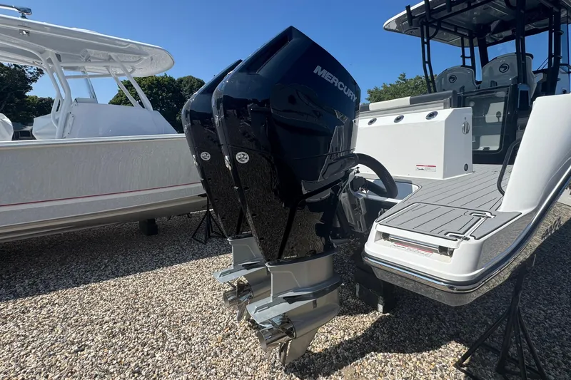 Slide: The Image of 2025 Edgewater 340CC boat with dual Mercury engines on display outdoors. - 6