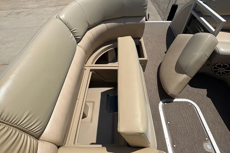 Slide: The Image of 2012 Bennington 2575 QCW I/O boat interior with beige seating and storage compartments. - 11
