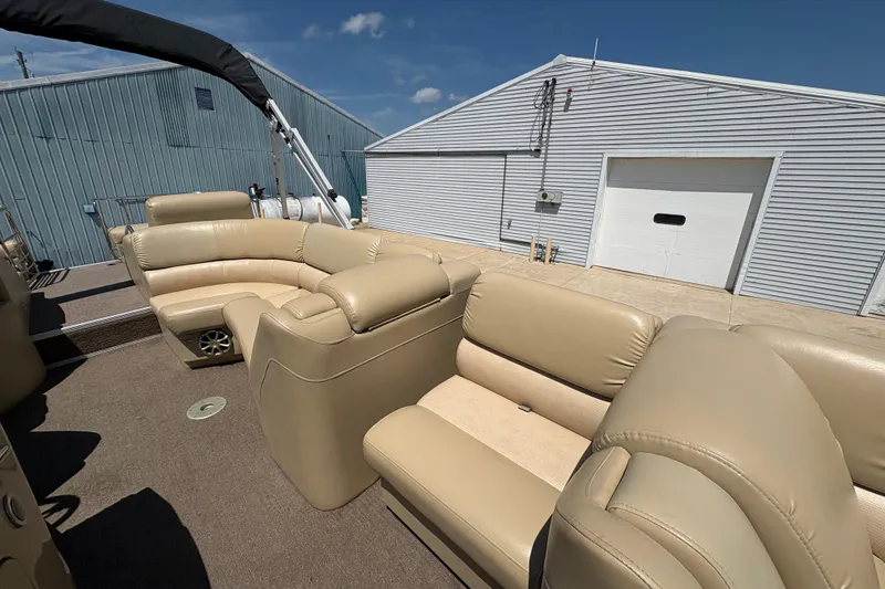 Slide: The Image of 2012 Bennington 2575 QCW I/O boat with beige seating, docked near a metal building. - 13