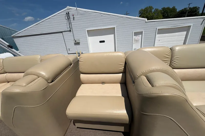 Slide: The Image of 2012 Bennington 2575 QCW I/O boat with beige leather seating, parked near a white garage. - 14