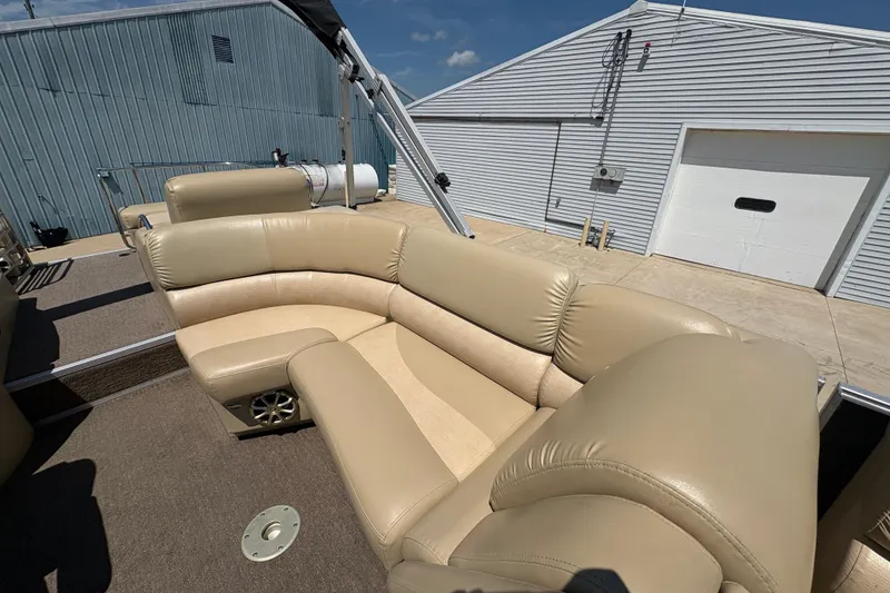Slide: The Image of 2012 Bennington 2575 QCW I/O boat with beige leather seating, docked near a warehouse. - 19