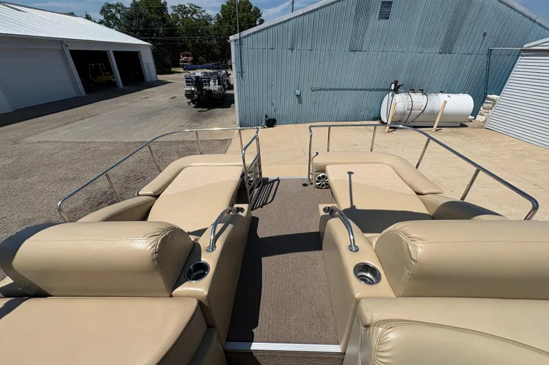 Slide: The Image of 2012 Bennington 2575 QCW I/O boat with beige seating and metal railings in a marina. - 21