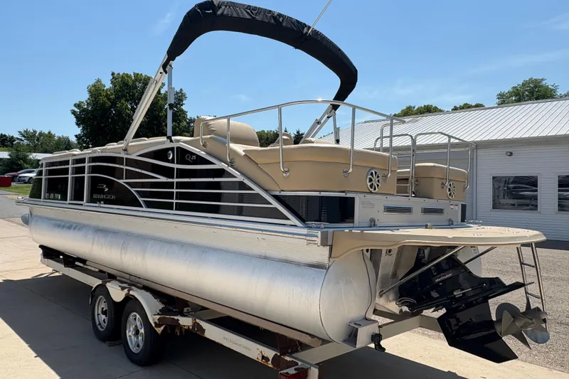 Slide: The Image of 2012 Bennington 2575 QCW I/O pontoon boat on trailer, parked outdoors. - 3