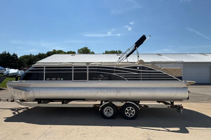 Slide: The Image of 2012 Bennington 2575 QCW I/O pontoon boat on trailer, parked outdoors. - 4