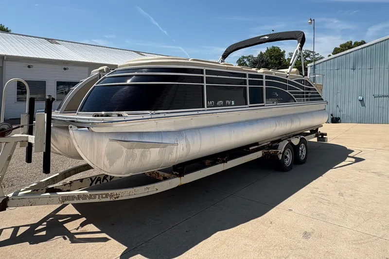 Slide: The Image of 2012 Bennington 2575 QCW I/O pontoon boat on trailer, parked outside a building. - 5
