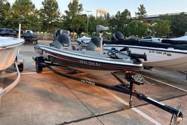 Slide: The Image of 2014 Nitra Boats Z6 on trailer in parking lot, surrounded by trees and other boats. - 1