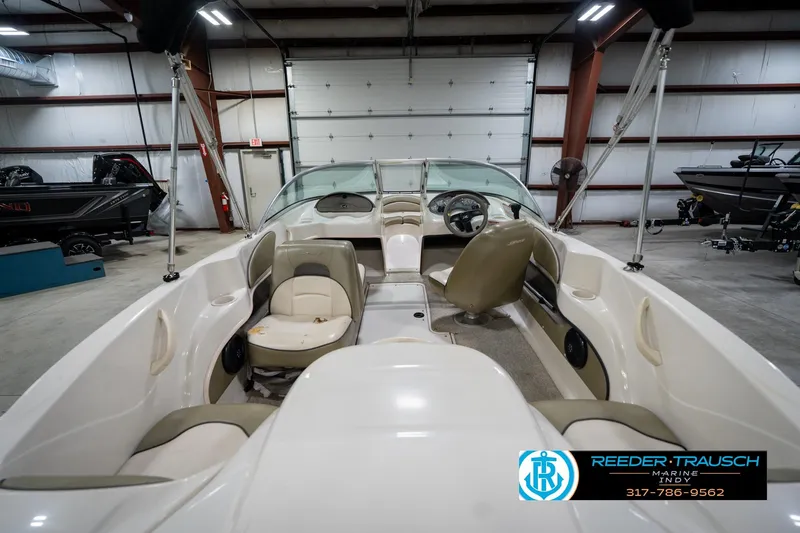 Slide: The Image of 2005 Sea Ray 180 Sport boat interior in showroom, featuring beige seating and open bow design. - 20