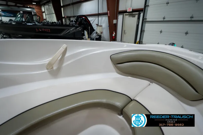 Slide: The Image of 2005 Sea Ray 180 Sport boat interior with cushioned seating and handle, displayed in showroom. - 37