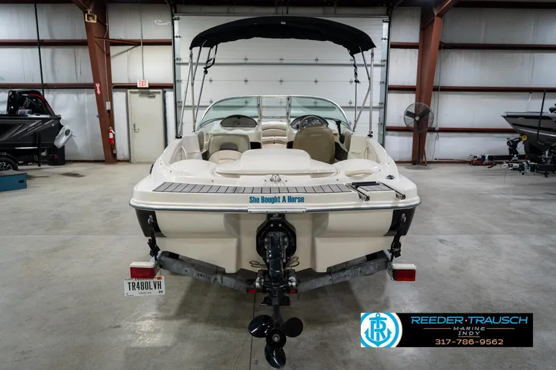 Slide: The Image of 2005 Sea Ray 180 Sport boat in showroom, featuring sleek design and trailer. - 9