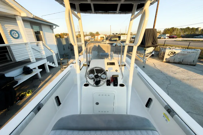 Slide: The Image of 2026 Carolina Skiff 19 LS boat interior with steering console, docked near a building. - 17