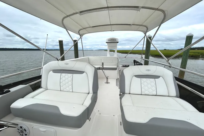 Slide: The Image of 2024 Regal 42 FXO boat interior with cushioned seating and canopy on a calm waterway. - 10