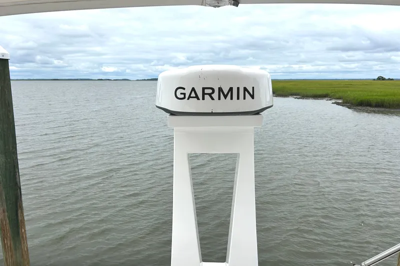 Slide: The Image of Garmin radar on 2024 Regal 42 FXO boat, overlooking serene water and grassy shoreline. - 12