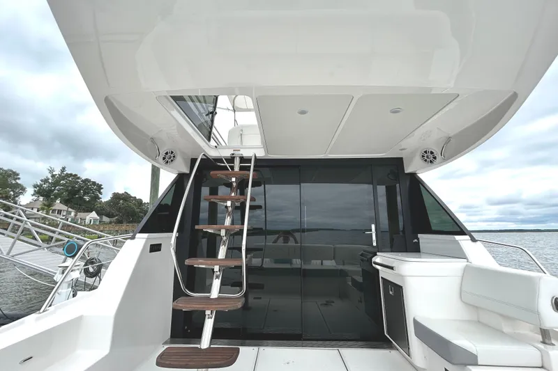 Slide: The Image of 2024 Regal 42 FXO yacht with sleek design, featuring outdoor seating and ladder access. - 3