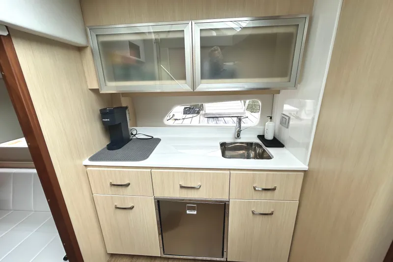 Slide: The Image of 2024 Regal 42 FXO yacht interior kitchen with sink, cabinets, and coffee maker. - 42