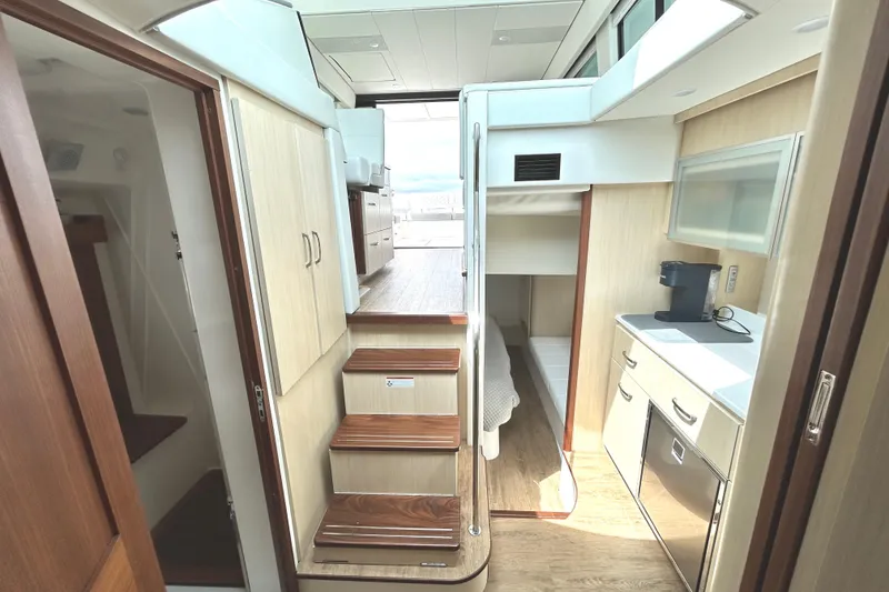 Slide: The Image of 2024 Regal 42 FXO yacht interior with modern kitchen, wooden stairs, and cozy sleeping area. - 48