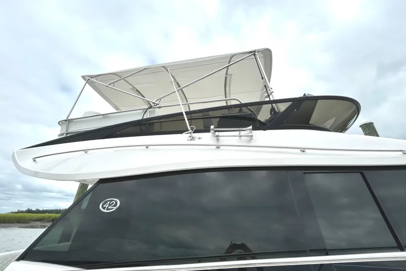 Slide: The Image of 2024 Regal 42 FXO yacht with sleek design and canopy, docked under cloudy skies. - 5