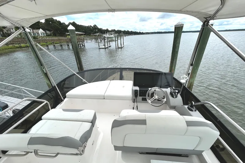 Slide: The Image of 2024 Regal 42 FXO yacht helm with modern controls, docked by serene waterfront. - 8