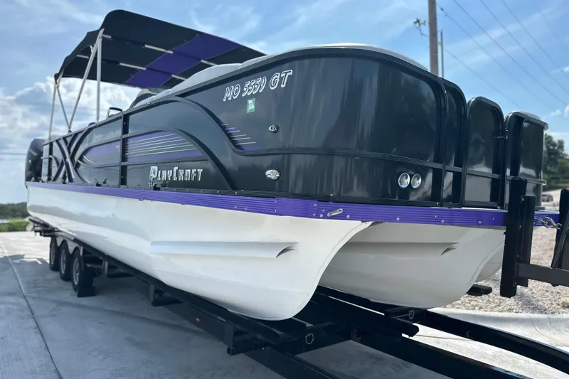 Slide: The Image of 2023 PlayCraft 2800 Extreme pontoon boat on trailer, featuring sleek black and purple design. - 16