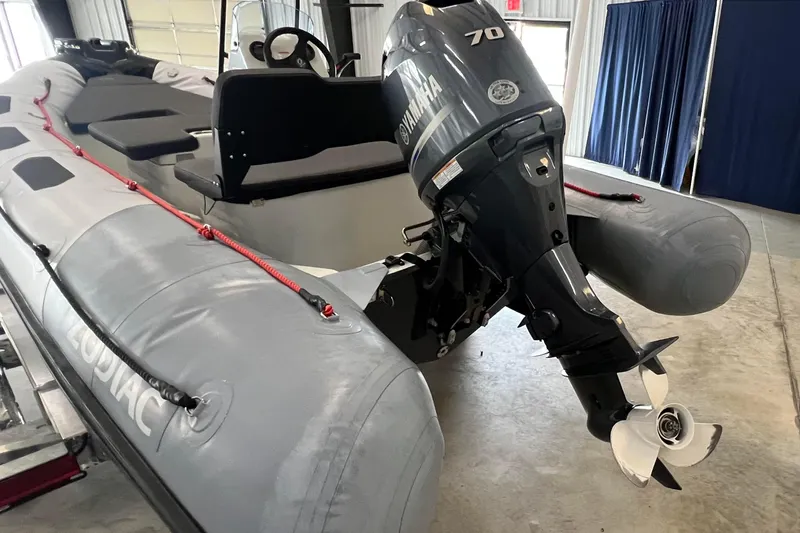 Slide: The Image of 2024 Zodiac Open 4.8 inflatable boat with Yamaha 70 outboard motor in a showroom. - 2