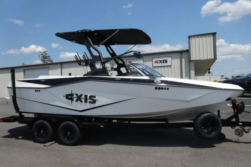 The Image of 2024 Axis T220 boat on trailer, parked outside dealership under blue sky. - 0
