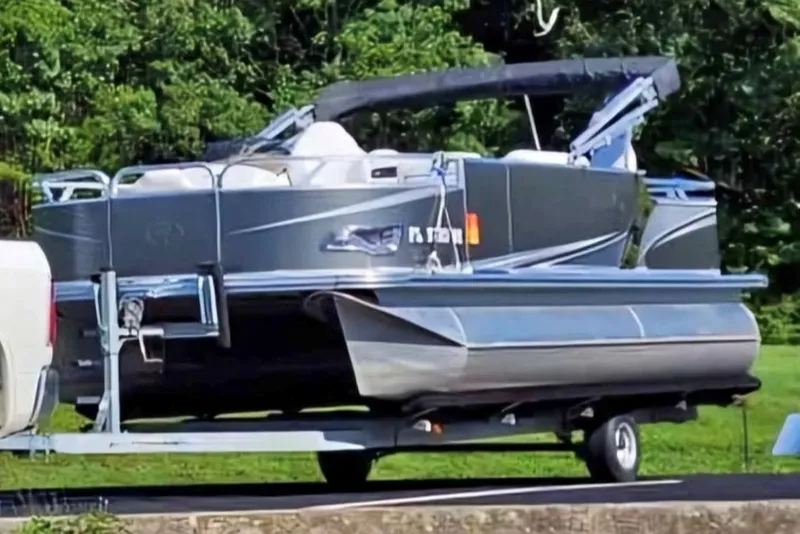 The Image of 2016 Avalon Catalina LSZ Fish 20' pontoon boat on trailer, parked near lush greenery. - 1