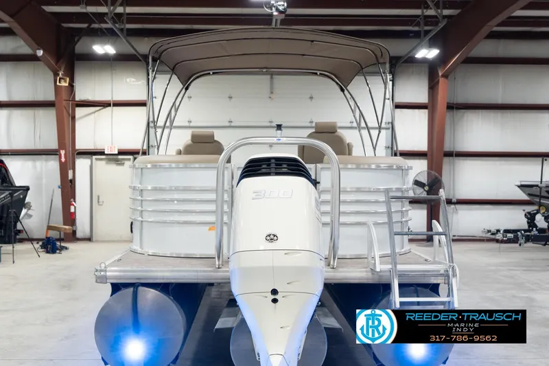 Slide: The Image of 2020 Leisurecraft 2435 LX pontoon boat in a warehouse, featuring a canopy and ladder. - 8