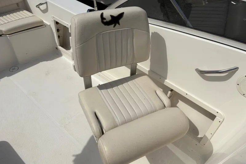 Slide: The Image of 2006 Mako 216 Dual Console boat seat with shark logo, white upholstery. - 15