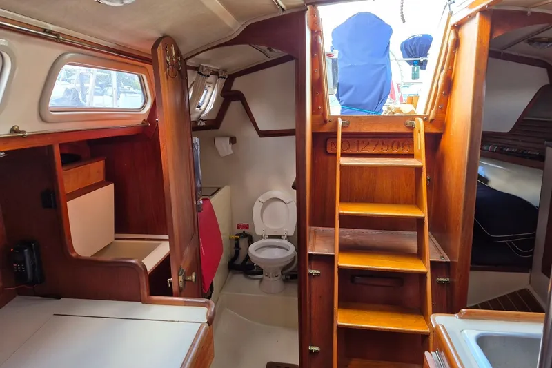 Slide: The Image of Interior of 1992 Pacific Seacraft Ericson 34 sailboat, featuring wooden cabinetry and compact toilet area. - 15