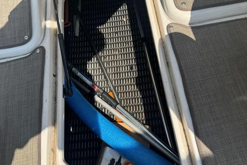 Slide: The Image of Storage compartment of 2001 Chaparral 220 SSi boat with fishing rods and blue pool noodle. - 33