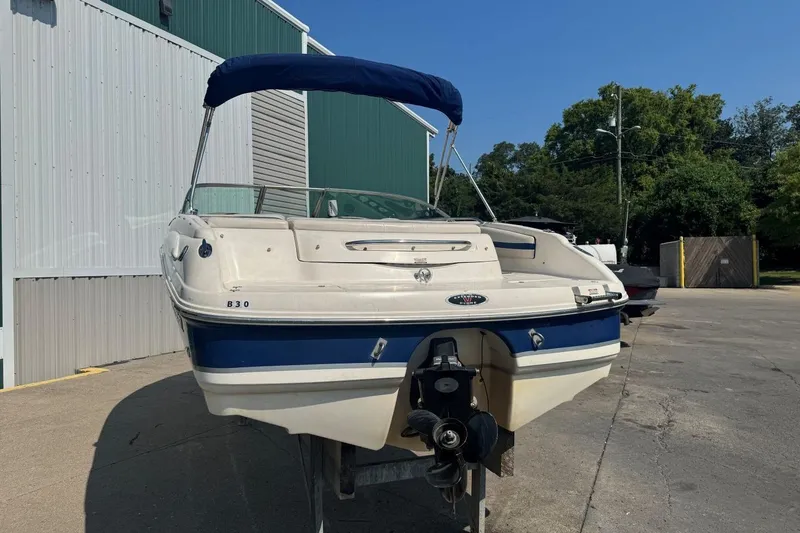 Slide: The Image of 2001 Chaparral 220 SSi boat with blue canopy, parked outdoors near a building. - 5