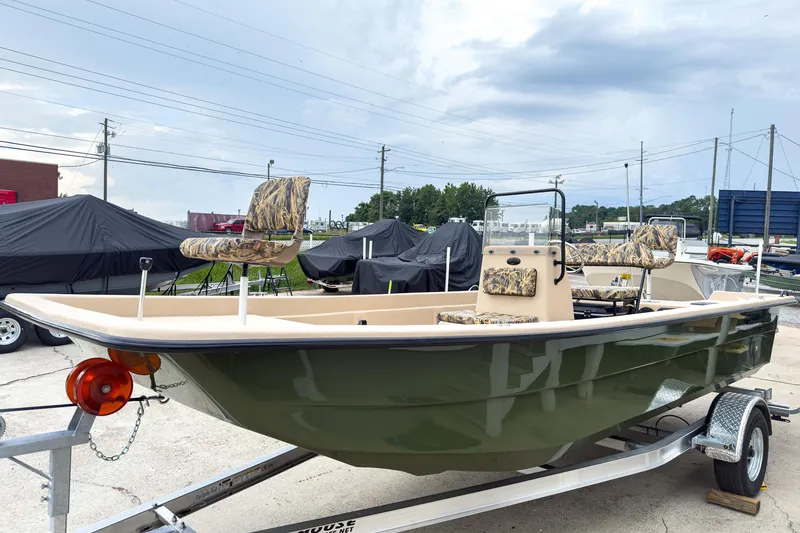 The Image of 2026 Carolina Skiff E21 DLX CC boat on trailer, featuring camouflage seating. - 0