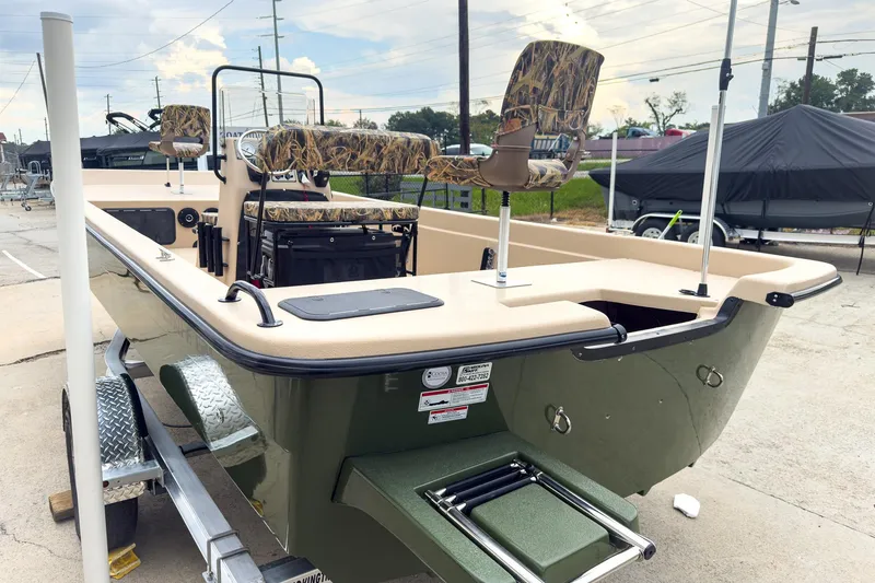 Slide: The Image of 2026 Carolina Skiff E21 DLX CC boat on trailer, featuring camo seats and green hull. - 2