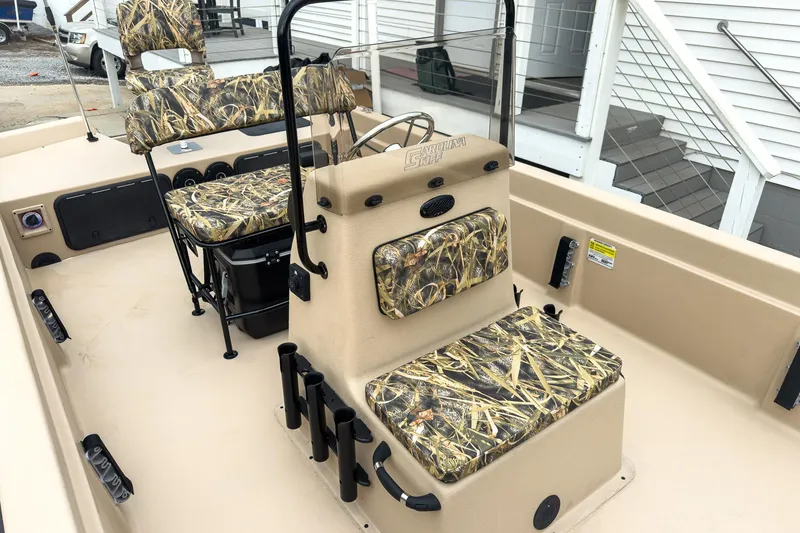 Slide: The Image of 2026 Carolina Skiff E21 DLX CC boat interior with camouflage seating and fishing rod holders. - 21