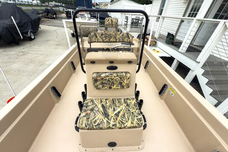 Slide: The Image of 2026 Carolina Skiff E21 DLX CC boat with camouflage seating, docked near a white building. - 24