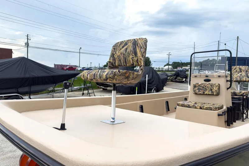Slide: The Image of 2026 Carolina Skiff E21 DLX CC boat with camo seats, parked outdoors. - 3
