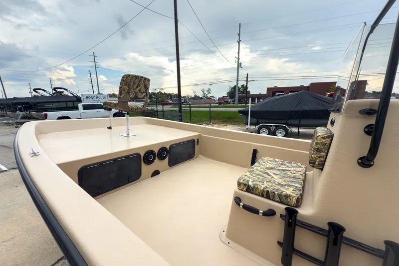 Slide: The Image of 2026 Carolina Skiff E21 DLX CC boat interior with camouflage seating, parked outdoors. - 4