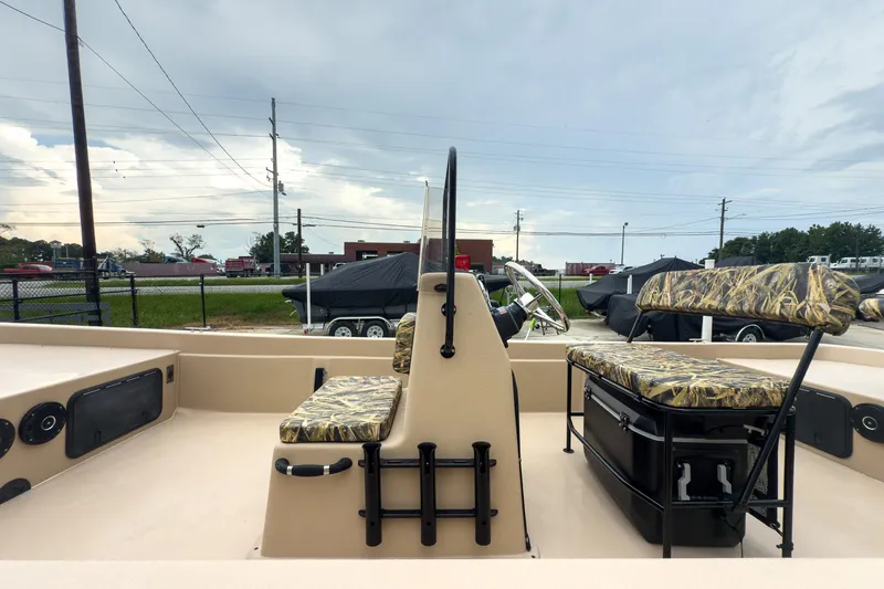 Slide: The Image of 2026 Carolina Skiff E21 DLX CC boat interior with camouflage seating and steering console. - 5