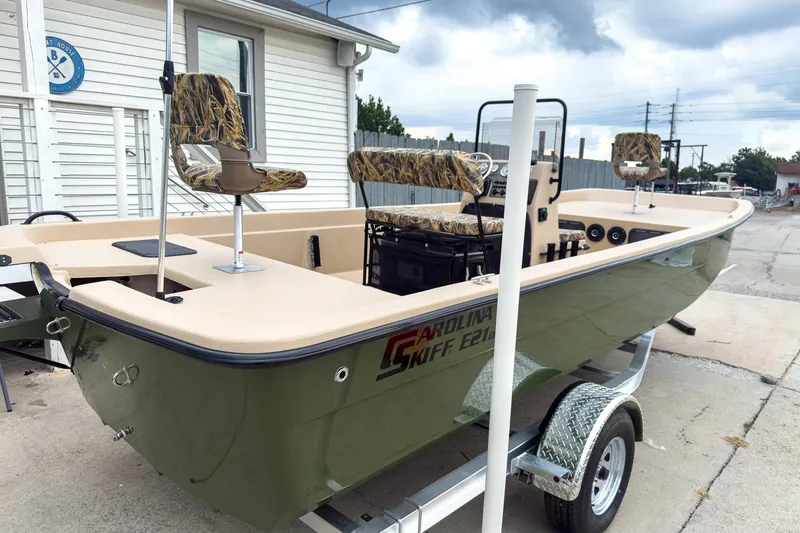 Slide: The Image of 2026 Carolina Skiff E21 DLX CC boat on trailer, featuring camouflage seats. - 7