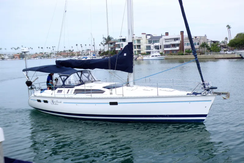 The Image of 1993 Hunter 40.5 sailboat docked in a marina, surrounded by waterfront homes. - 0