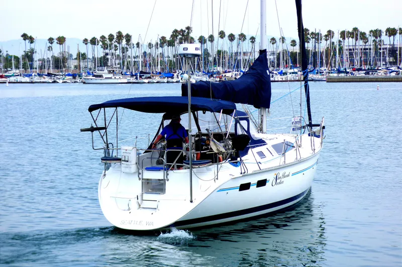 Slide: The Image of 1993 Hunter 40.5 sailboat cruising in marina with palm trees and docked boats in background. - 2